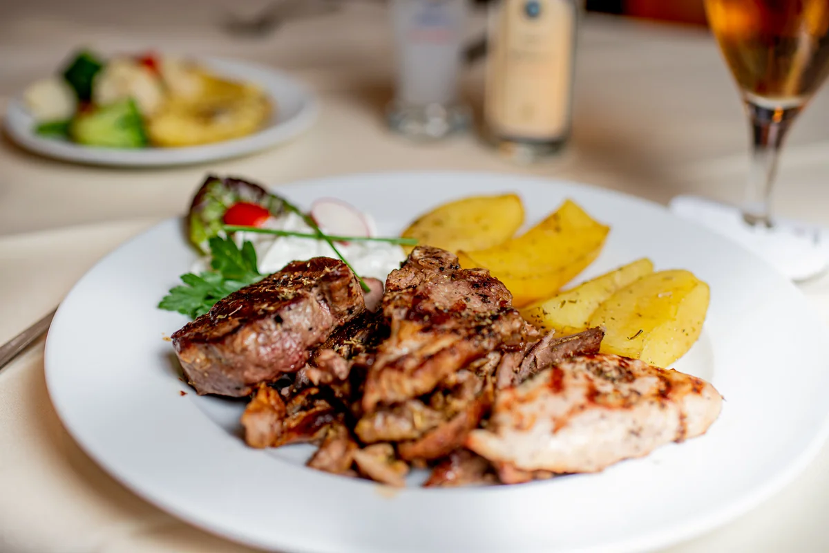 Grillplatte mit Rumpsteak, Gyros und Lammkoteletts, dazu Ofenkartoffeln und Salat