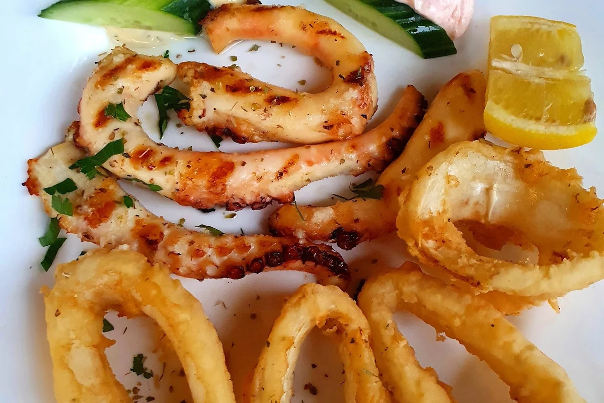 Gegrillte Oktopusarme und frittierte Calamari-Ringe mit Zitrone und Gurke