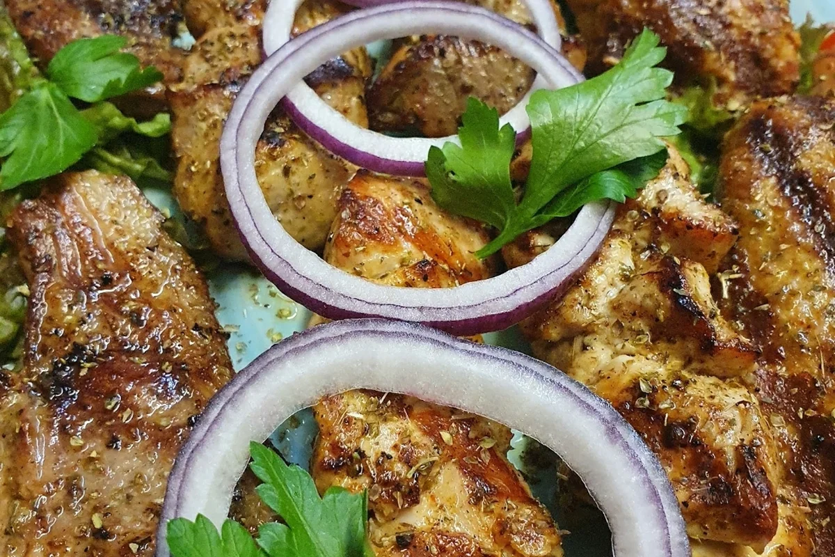Gegrillte Fleischstücke vom Spieß mit roten Zwiebelringen und Petersilie