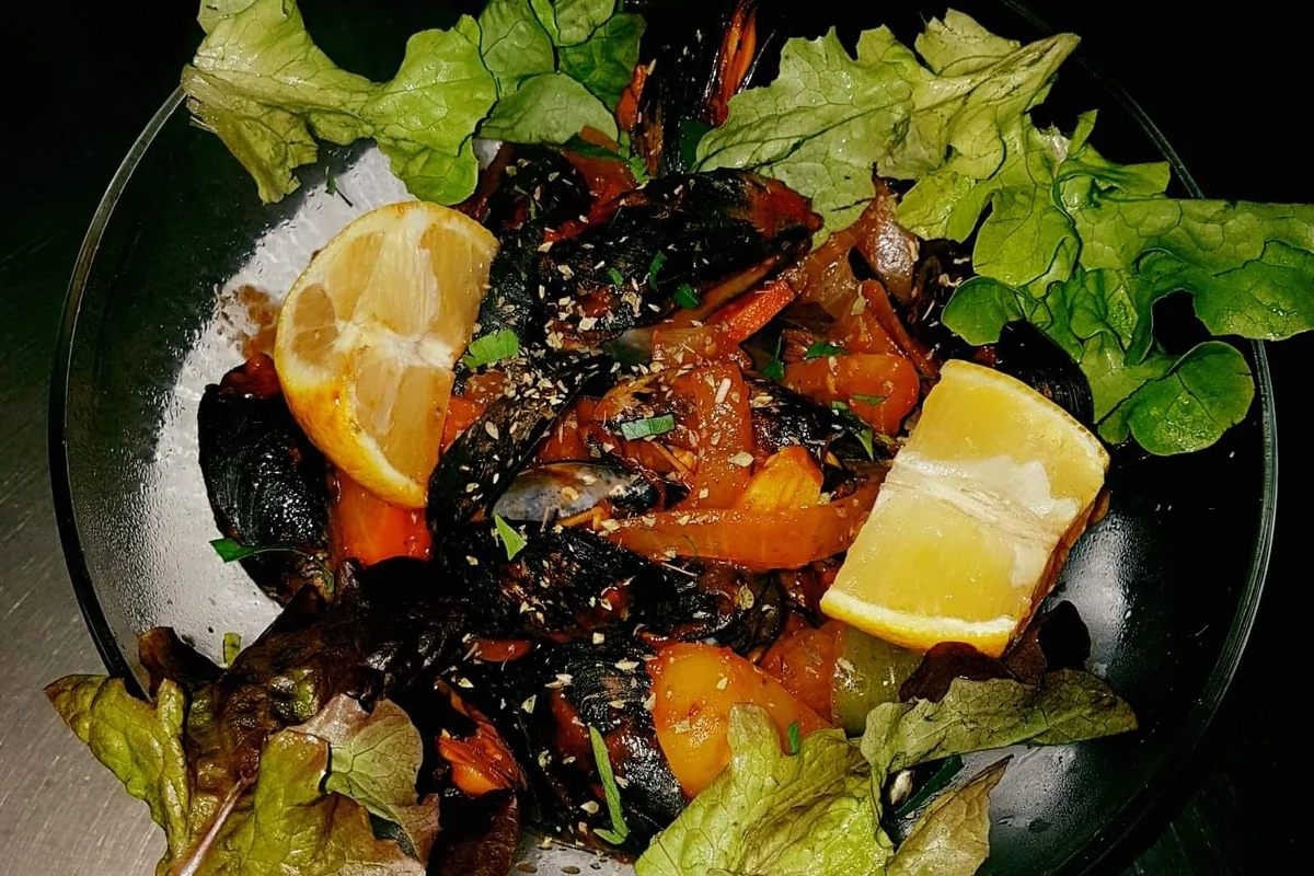 Miesmuscheln mit Tomaten, Zitrone und Salat in einer Glasschale
