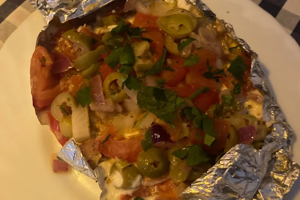 In Alufolie gebackenes Gericht mit Tomaten, grünen Oliven, Peperoni und Petersilie