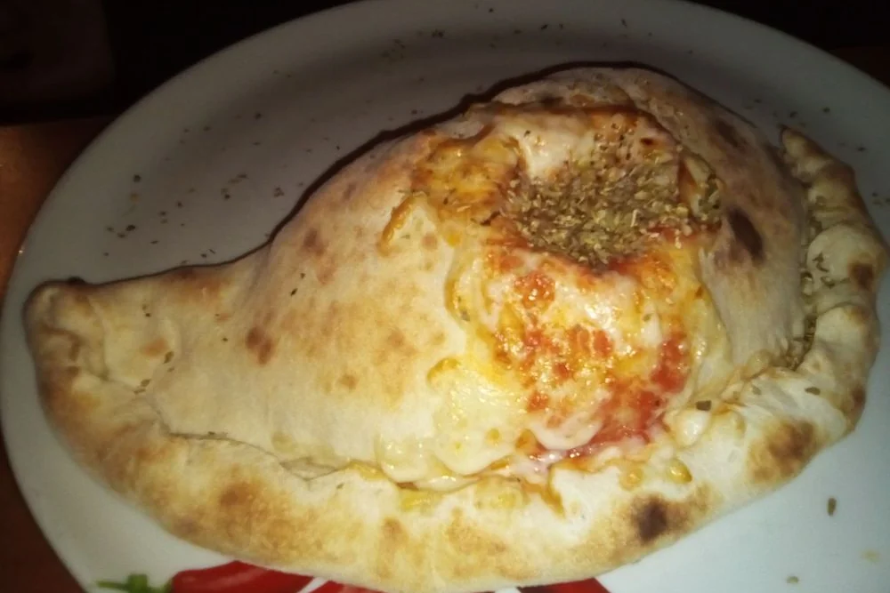 Goldbraun gebackene Calzone mit Kräutern, aufgebrochen an der Seite