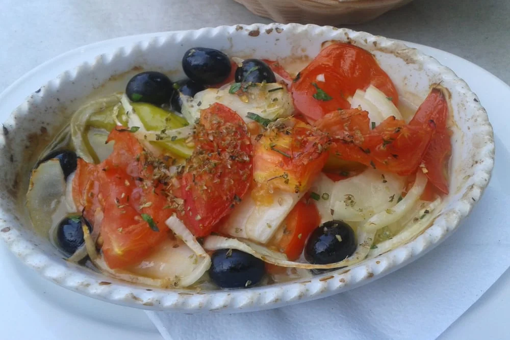 Ofengebackenes Gericht mit Tomaten, Zwiebeln, schwarzen Oliven und Peperoni in einer ovalen Form
