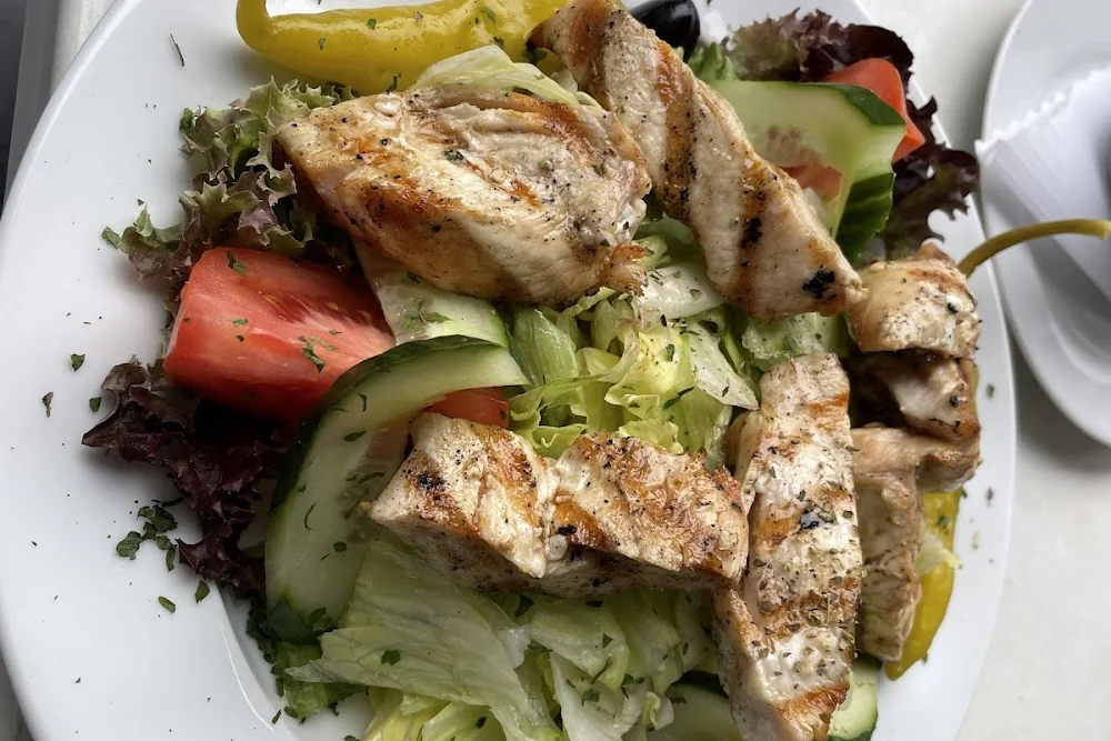 Gegrillte Hähnchenbruststreifen auf gemischtem Salat mit Tomate, Gurke und Peperoni