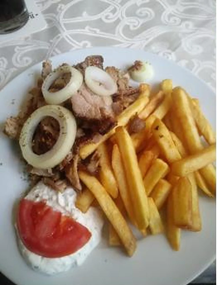 Gyros-Teller mit Zwiebelringen, Pommes frites, Tzatziki und Tomate