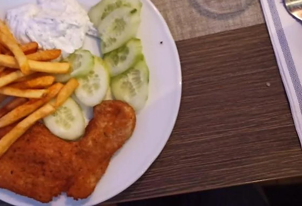 Schnitzel mit Pommes frites und Gurkensalat auf weißem Teller