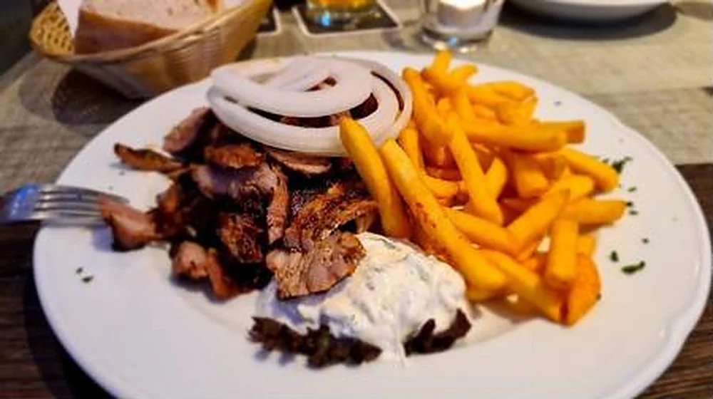 Gyros mit Pommes frites, Tzatziki und Zwiebeln auf einem Teller