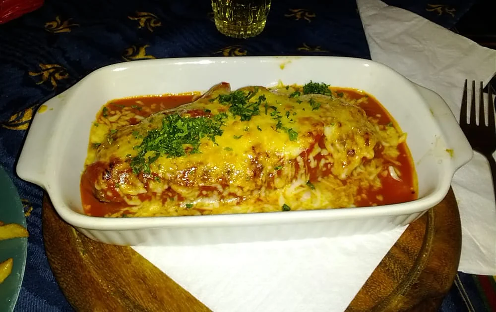 Mit Käse überbackener Auflauf in Tomatensoße in weißer Auflaufform mit Petersilie