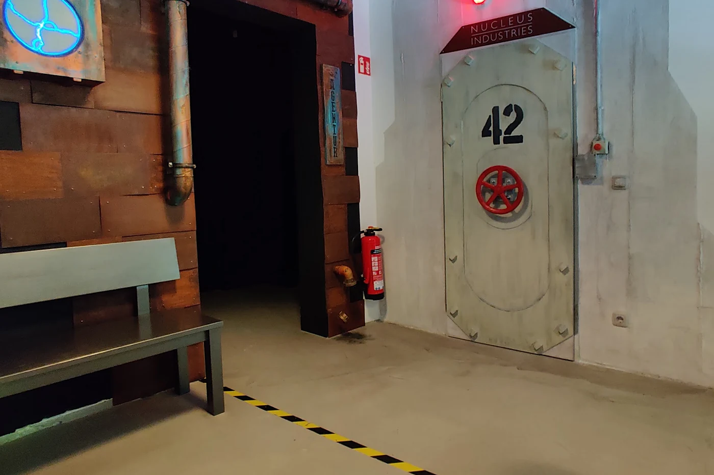 Flur mit Backsteinwand, Rohren und einer schweren grauen Schleusentür mit der Nummer 42 und rotem Handrad