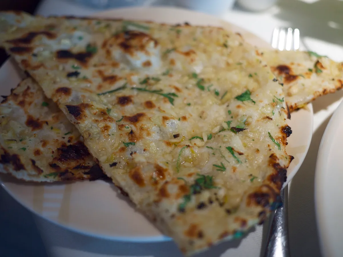 Frisch gebackenes Naanbrot mit Knoblauch und Koriander auf einem weißen Teller