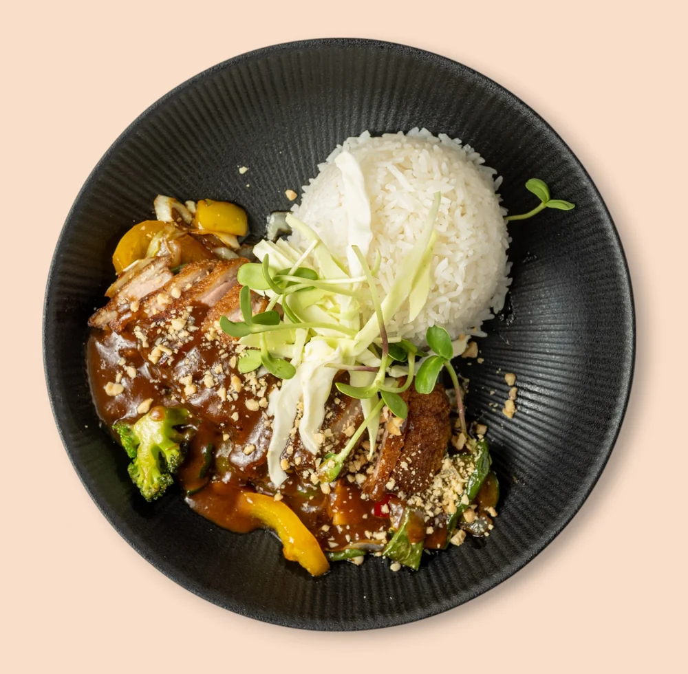 Knusprige Ente mit Gemüse in dunkler Sauce, Jasminreis und Sprossen auf schwarzem Teller