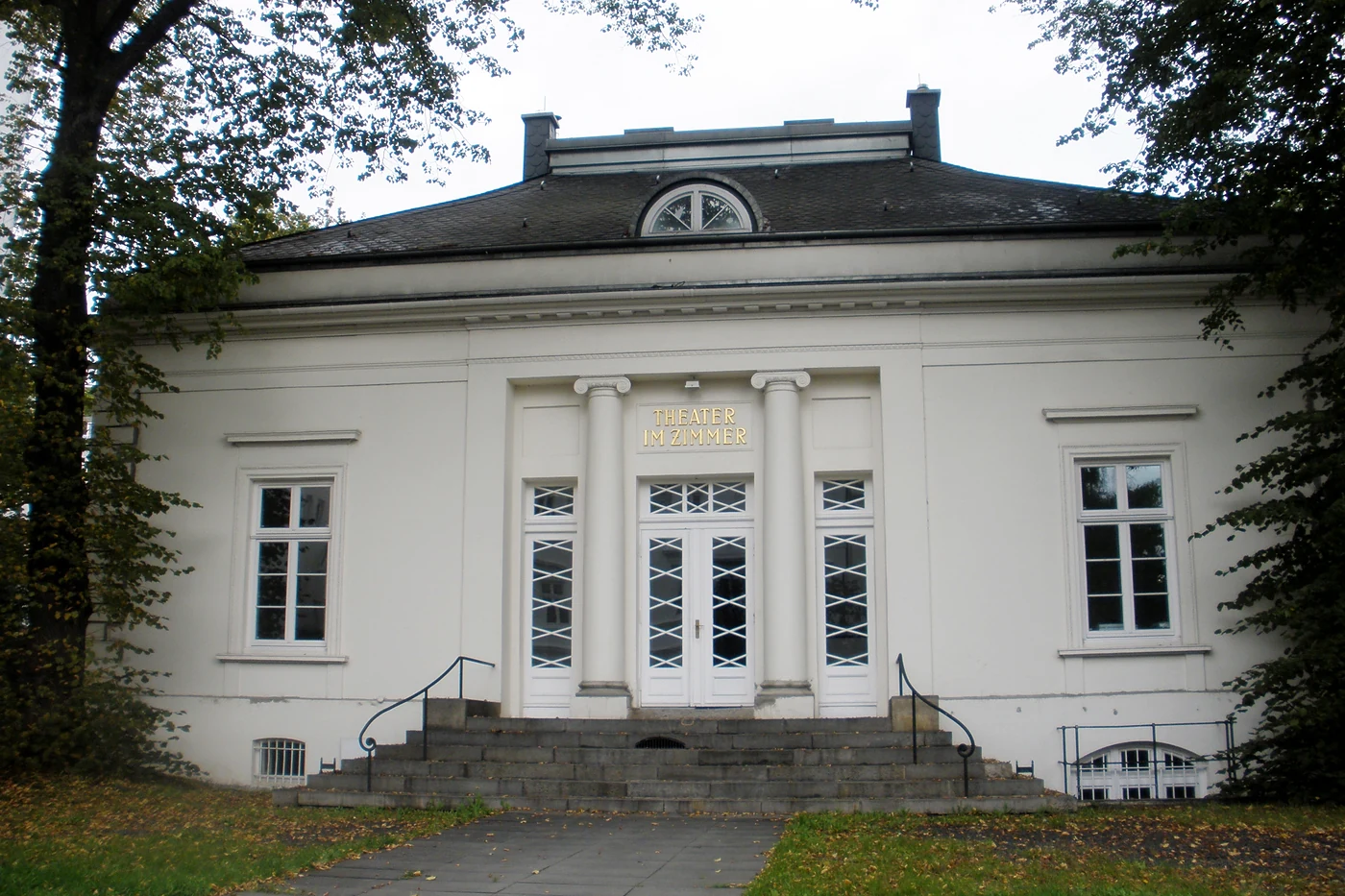 Frontansicht der weißen Villa mit Freitreppe und halbrundem Giebelfenster