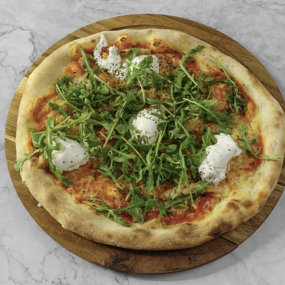 Pizza mit Büffelmozzarella, Rucola und Tomaten auf Holzbrett
