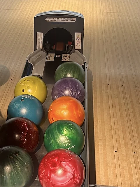 Bunte Bowlingkugeln in Gelb, Blau, Lila, Orange, Rot und Grün in der Kugelrückführung einer Bahn