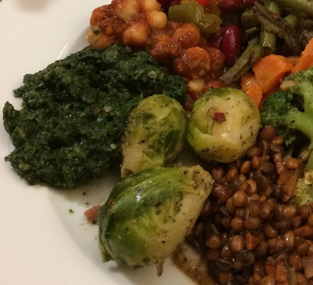 Nahaufnahme eines Antipasti-Tellers mit Rahmspinat, Rosenkohl, Linsen, Kichererbsen und Brokkoli