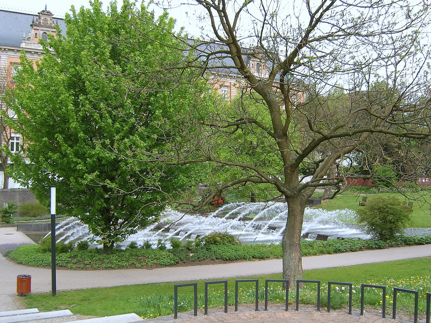 Wasserkaskaden in den Wallanlagen mit Bäumen und Gebäuden im Hintergrund