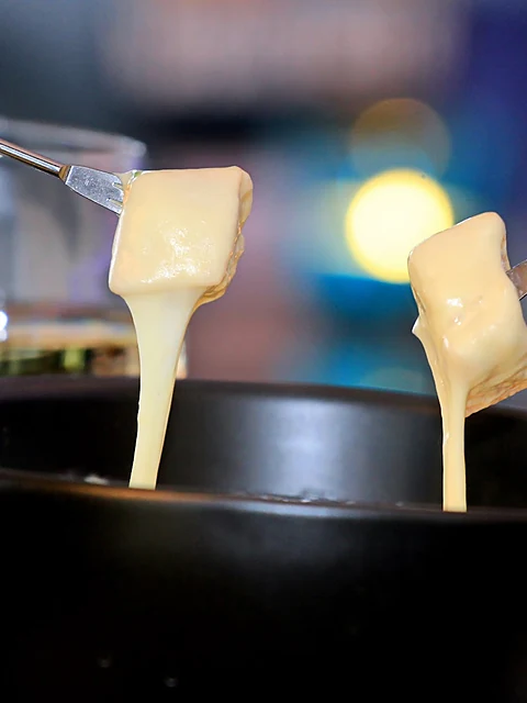 Käsefondue mit zwei Gabeln voller geschmolzenem Käse über dem Topf