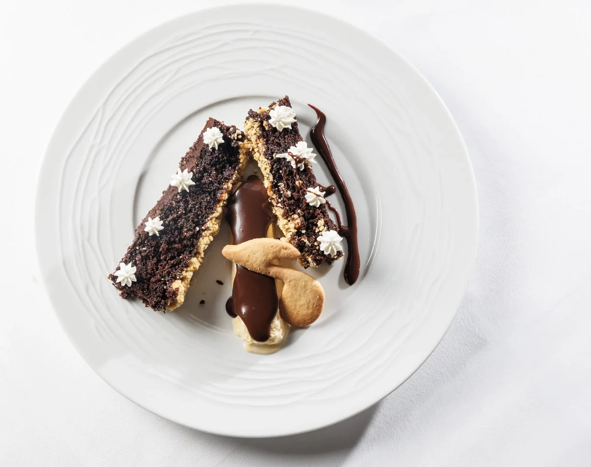 Schokoladenkuchen mit Schokosauce und Gebäck auf weißem Teller