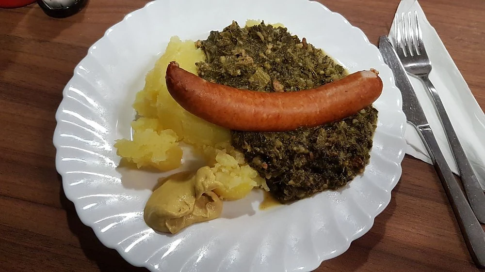 Grünkohl mit Kochwurst und Kartoffeln auf weißem Teller