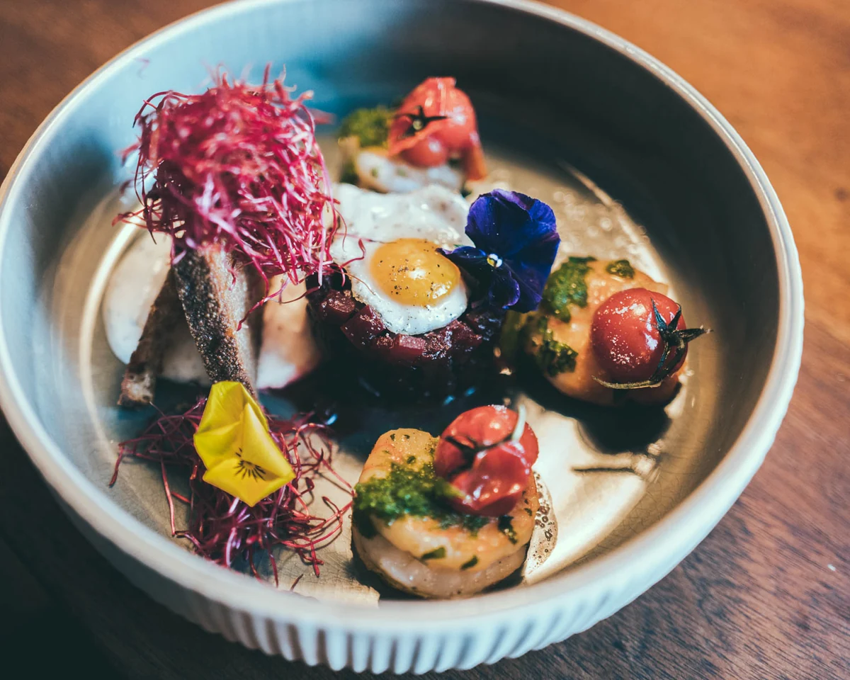 Teller mit Tatar, pochiertem Ei, Tomaten und Rote-Bete-Streifen