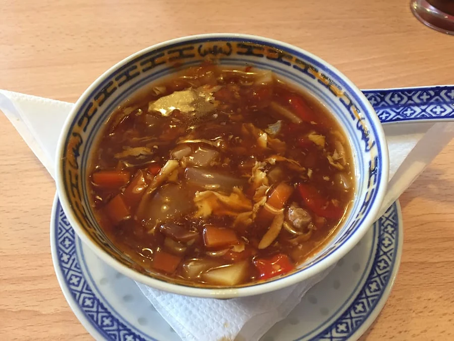 Scharf-saure Pekingsuppe mit Gemüse und Ei in blau gemusterter Schale