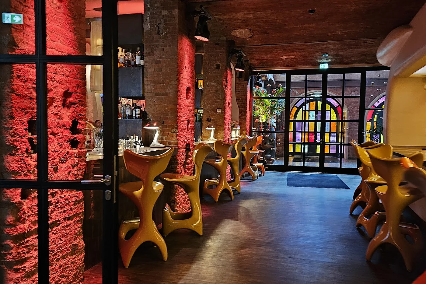 Bereich der Yakshi’s Bar mit organisch geformten goldenen Barhockern vor rohen Rotklinkersäulen