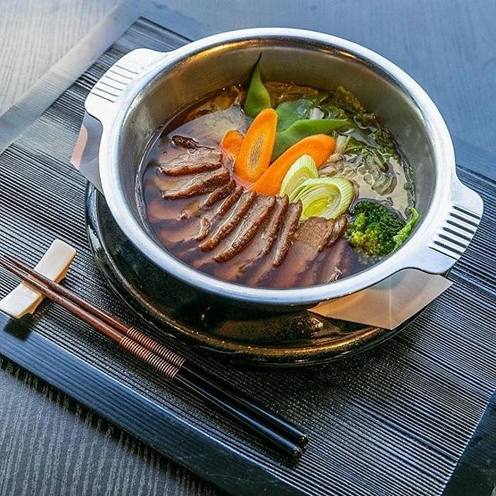 Nabeyaki-Udon: Nudelsuppe mit Fleischscheiben, Möhre und Brokkoli im Metalltopf