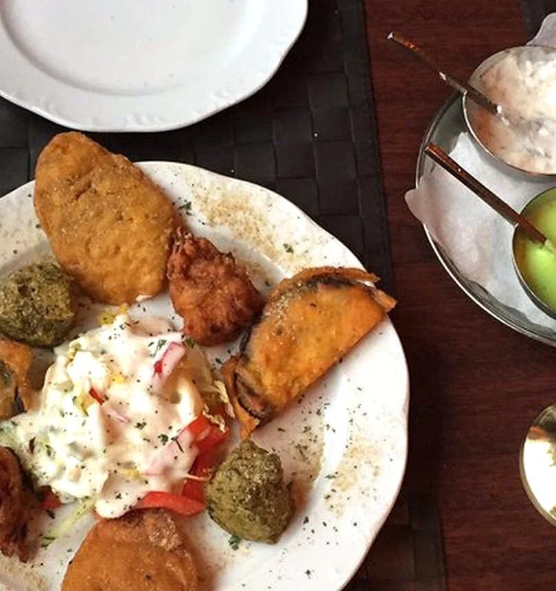 Teller mit gemischten Pakoras, Dips in kleinen Schalen und Papadam