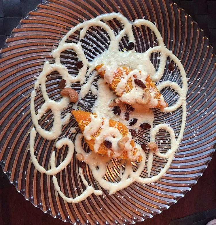Scampi Tikka mit heller Sauce und Cashewkernen auf gemustertem Teller