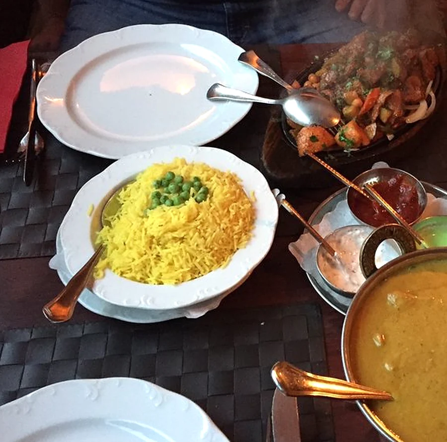 Gedeckter Tisch mit Basmatireis, Currytopf, Tikka-Pfanne und Dips